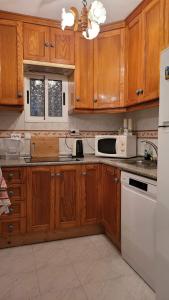 una cocina con armarios de madera y electrodomésticos blancos en Villa Lenia, en Torrevieja