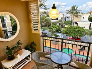a balcony with a table and chairs and a view of a pool at 'Little Mermaid' beach apartment best location walk to beach and restaurants - sleeps 4 in Gold Coast