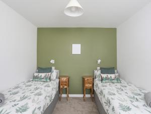 a bedroom with two beds and a night stand at Y Goedwig in Llanfairpwllgwyngyll