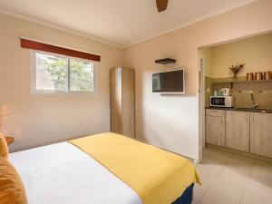 a bedroom with a bed with a yellow blanket at Lotan Desert Travel Hotel in Naẖal Ya‘alon