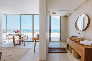 a bathroom with a sink and a dining room with a table at Serenity Villa on the Cliff with climatized pool in Sauzal