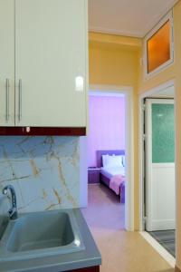 a kitchen with a sink and a room with a bed at Brothers LR in Sarandë