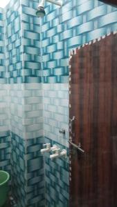 a bathroom with a shower with blue and white tiles at Gopi Dham Hotel in Vrindāvan