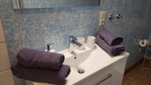ein Badezimmer mit einem Waschbecken und lila Handtüchern darauf in der Unterkunft Am Fuße zur Napoleonschanze in Hohnstein
