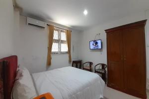1 dormitorio con 1 cama, armario y TV en OYO 92463 Deli Hotel Medan, en Medan