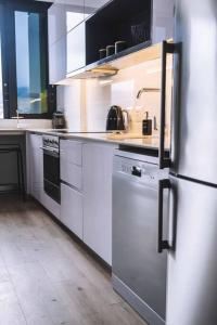 uma cozinha com armários brancos e um frigorífico de aço inoxidável em Stylish one bedroom with stunning Lion's Head & Table Mountain views na Cidade do Cabo