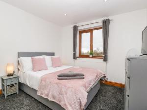 a bedroom with a bed with a pink blanket and a window at Delphine Lodge, Meadow View Lodges in Burnham on Sea
