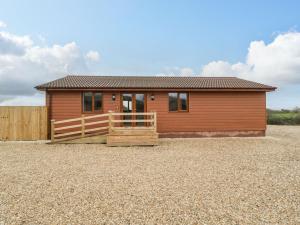 una pequeña casa con una valla delante de ella en Delphine Lodge, Meadow View Lodges, en Burnham-on-Sea
