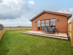 een huis met een terras met een tafel en stoelen bij Delphine Lodge, Meadow View Lodges in Burnham on Sea