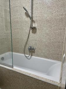 a bath tub with a shower with a glass door at Апартаменти Парус біля Вікторії Гарденс, Південого in Lviv