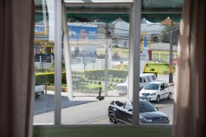 una vista da una finestra di auto parcheggiate su una strada di HOTEL TROPICAL a Curitiba