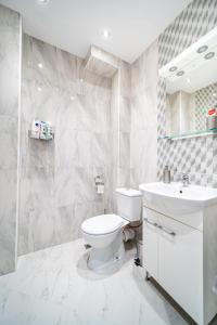 a white bathroom with a toilet and a sink at Bright and Elegant Apartment in Varna City