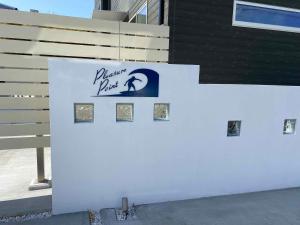 IchinomiyaにあるPleasure Point Ichinomiyaのフェンスの横にある看板の付いた白い壁