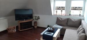 ein Wohnzimmer mit einem Sofa und einem Flachbild-TV in der Unterkunft Pension-Nussbaum in Grünewalde