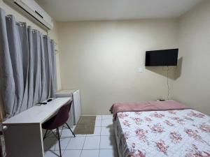 a bedroom with a bed and a desk and a television at Kadosh in São Luís