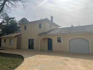 a white house with two garage doors and a driveway at Maison de vacances avec piscine in Chancelade