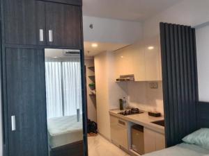a room with a bed and a kitchen with a window at APARTEMEN SKY HOUSE BSD in Samporo