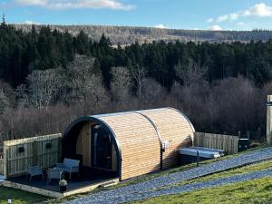 un edificio de madera con un banco en un campo en Highland Premier Glamping Pods en Beauly
