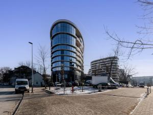 a tall glass building with a car parked in a parking lot at Malila Premium Apartments Cracow Centre Wiślane Tarasy 2 0 in Krakow