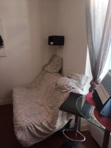 ein kleines Schlafzimmer mit einem Bett, einem Schreibtisch und einem Laptop in der Unterkunft Studio De La Gare in Vallauris