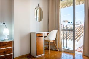 a room with a desk and a chair and a balcony at Hostal Cuevas in Fuengirola