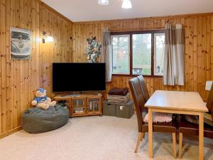 a living room with a flat screen tv and a table at Merlins Cabin in Cenarth