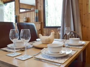 a wooden table with plates and wine glasses on it at Merlins Cabin in Cenarth