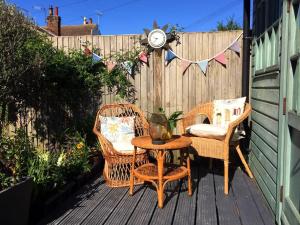 un patio con 2 sillas, una mesa y un reloj en una valla en Heart house fisherman’s cottage, en Kent