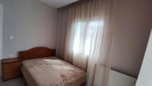 a bedroom with a bed and a window with curtains at La Casa Delle Vacanze in Neos Marmaras