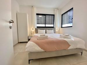 a bedroom with a large bed with two windows at 8 Hulda - By Beach Apartments TLV in Tel Aviv
