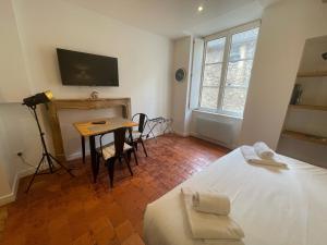 a bedroom with a bed and a table and a television at Le Studio Maufoux - Studio à 200m des Hospices de Beaune in Beaune +4 photos