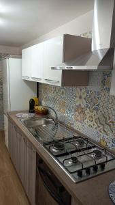 uma cozinha com um fogão e armários brancos em Scirocco e Maestrale em Petrosino