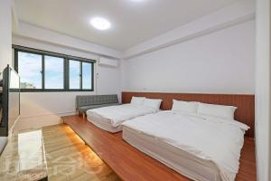 1 dormitorio blanco con 2 camas y ventana en 忘憂海HappinesSea, en Xiyu