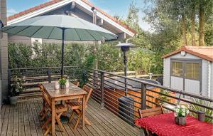 una terraza de madera con mesa y sombrilla en Lovely Home In Bourbourg With Kitchen en Bourbourg