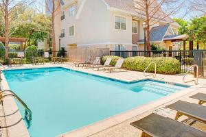 a swimming pool with chairs and a house at Residence Inn Dallas Park Central in Dallas