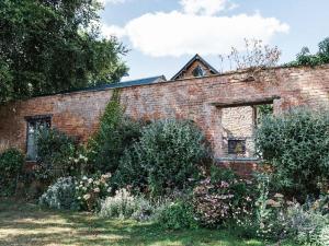 an old brick building with a garden in front of it at Blackrock Barn in Clifford