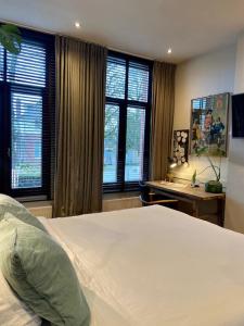 een slaapkamer met een groot wit bed en ramen bij B&B Toast Hoogstraten in Hoogstraten