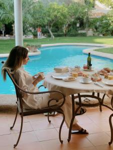 a woman sitting at a table near a pool at Son Sant Jordi Boutique House in Pollença