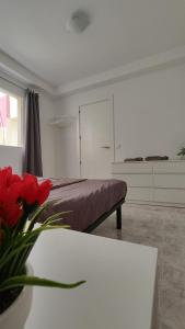 ein Schlafzimmer mit einem Bett und einem Tisch mit einer Blumenvase in der Unterkunft Fabelo Apartment, Puerto del Rosario in Puerto del Rosario