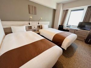 a hotel room with two beds and a television at Smile Hotel Premium Hakodate Goryokaku in Hakodate