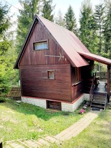 duży drewniany dom z czerwonym dachem w obiekcie Chatka Nad Strumieniem w mieście Glinka