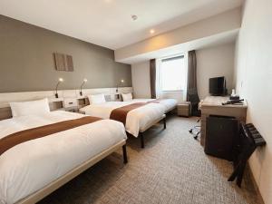 a hotel room with two beds and a television at Smile Hotel Premium Hakodate Goryokaku in Hakodate
