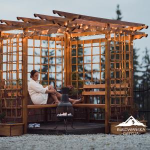 a woman sitting on a bench in a gazebo at Bukowiańska Ostoja in Bukowina Tatrzańska