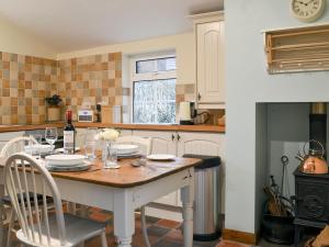 a kitchen with a table and chairs and a stove at Caeberllan in Llanfair Caereinion