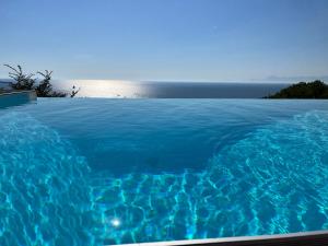 a blue swimming pool with the ocean in the background at A La Puesta Del Sol in Agropoli