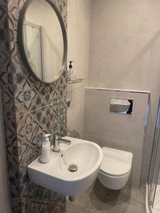 a bathroom with a sink and a mirror and a toilet at Friendly Apartment in Krakow