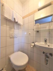 La salle de bains blanche est pourvue de toilettes et d'un lavabo. dans l'établissement Pension Schwartzwirt, à Neusiedl am Steinfelde