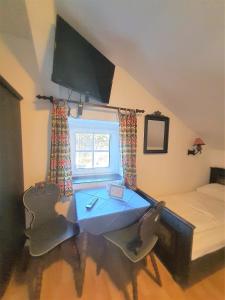 ein Schlafzimmer mit einem Tisch, einem Bett und einem Fenster in der Unterkunft Pension Schwartzwirt in Neusiedl am Steinfelde