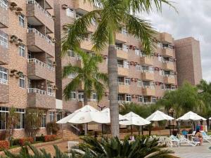 a hotel with tables and umbrellas in front of a building at Apartamento em Resort in Barreirinhas