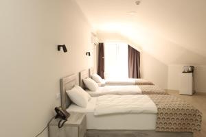 a white bedroom with four beds and a window at Aventus Hotel in Akhaltsikhe